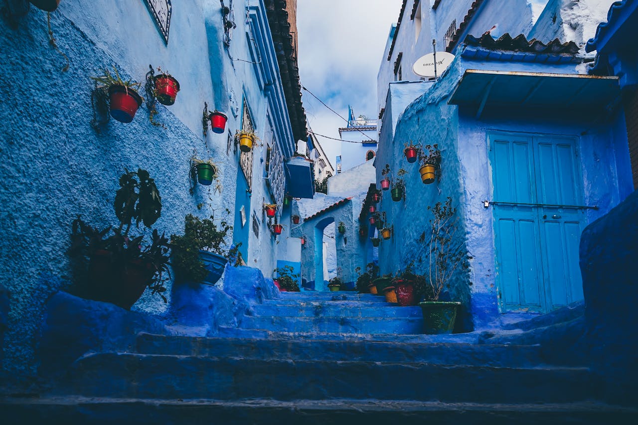 Colorful pots line the blue-washed walls of a narrow alley in Chefchaouen, Morocco.